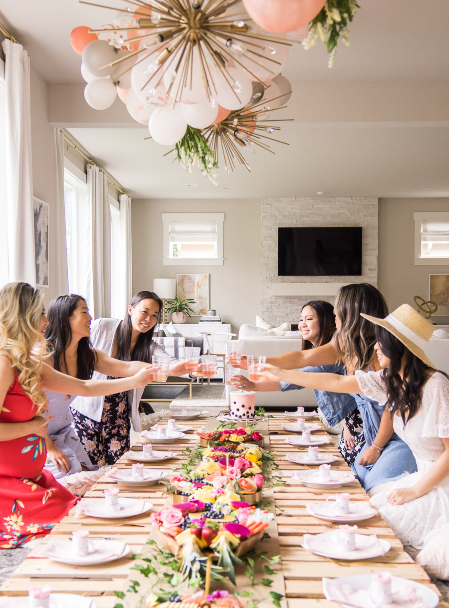 Friends raising glasses at a bright boho bridal shower table